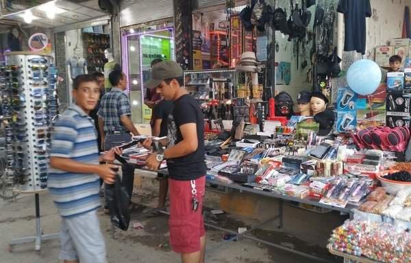 De jeunes hommes font les courses dans un marché à Ramadi. "L'Etat islamique en Irak et au Levant" a forcé les hommes à faire pousser les barbes et adhérer aux codes vestimentaires islamiques sous son règne. [Saif Ahmed/Diyaruna]