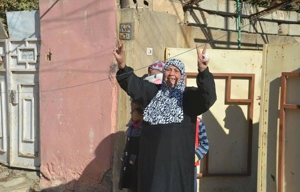 Une femme irakienne dans la zone d'al-Mouharibeen à Mossoul fait le signe de victoire quand les forces de sécurité traversent leur quartier après l'avoir libéré de "l'Etat islamique en Irak et au Levant" le 24 novembre. [Photo fournie par l'unité des forces spéciales irakiennes]