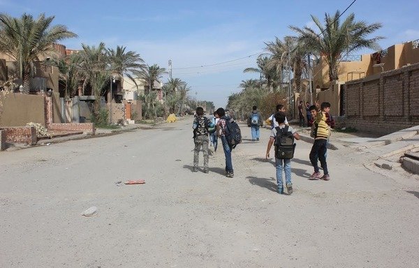 Des enfants de l'école élémentaire al-Asmai à Falloujah marchent joyeusement dans la rue, retournant chez eux après l'école. [Saif Ahmed/Diyaruna]