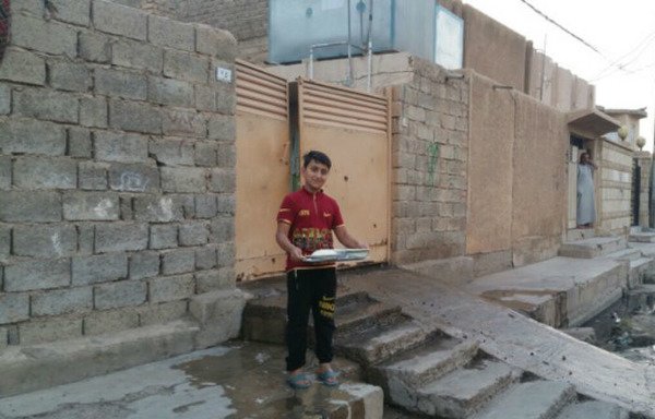 شاب عراقي يحمل بعد الإفطار صينية طعام إلى جيرانه، وهي عادة رمضانية أبقى العراقيون عليها.
