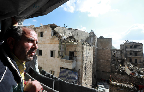 Izzat al-Dahan se tient au balcon de son appartement d'Alep le 11 février, dans le district de Salaheddine anciennement aux mains de l'opposition. [Louai Beshara/AFP]