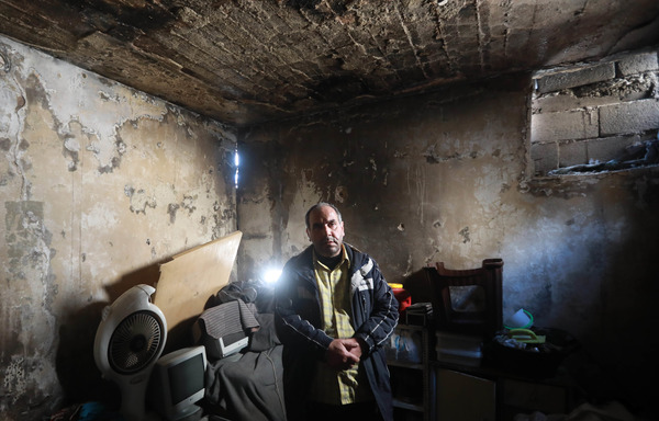 Izzat al-Dahan se tient dans son appartement endommagé de Salaheddine à Alep le 11 février. D'abord déplacée par les combats, sa famille est aujourd'hui contrainte de se déplacer à nouveau, car le bâtiment est destiné à être détruit. [Louai Beshara/AFP] 