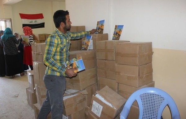 Employees at Fallujah's department of education receive new books for the new school year. Children were left without education for the past two years under ISIL. [Saif Ahmed/Diyaruna]