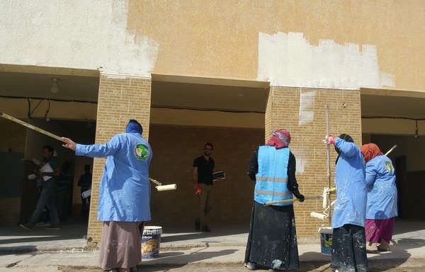 مجموعة من النساء تطوعن لطلاء جدران مدرسة إبتدائية في حي الشرطة وسط الفلوجة، في مسعى لإزالة شعارات داعش من المدارس. [سيف أحمد/ديارنا]