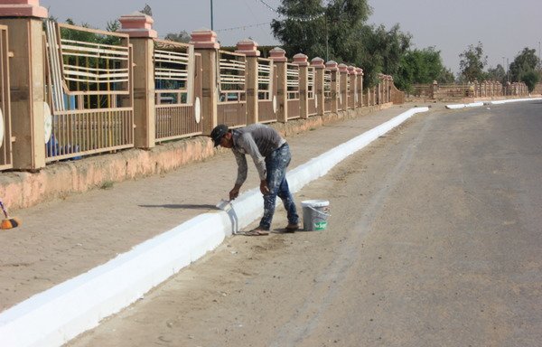 A municipal worker paints a sidewalk in al-Ihtifalat square in central Ramadi, known for the public celebrations it holds throughout the year. [Saif Ahmed/Diyaruna]