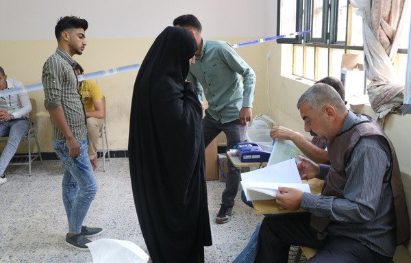A woman checks in to vote at al-Fallujah High School. Women in Anbar were oppressed during the rule of ISIS, which was defeated in the city last year. [Saif Ahmed/Diyaruna]