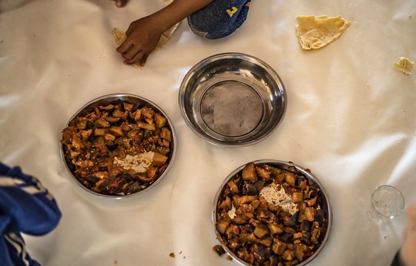 أطفال يتامى يتجمعون لتناول وجبة الغداء في مخيم عين عيسى تحت رعاية متطوعين. [دليل سليمان/وكالة الصحافة الفرنسية]