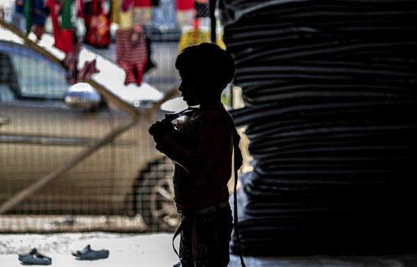 One of 24 orphaned children reportedly linked with ISIS foreign fighters is silhouetted at a camp in the northern Syrian village of Ain Issa. [Delil Souleiman/AFP] 