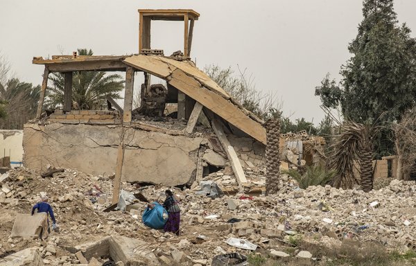 زنان اجناس را از زیر آوار یک خانه ویران شده در روستای باغوز در شرق سوریه در تاریخ ۱۳ مارس بازیافت میکنند. [دلیل سلیمان / خبرگزاری فرانسه]