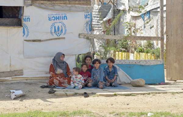 Inside the Saadnayel camp, a Syrian mother sits on the ground with her children. [Ziad Hatem/Al-Mashareq]