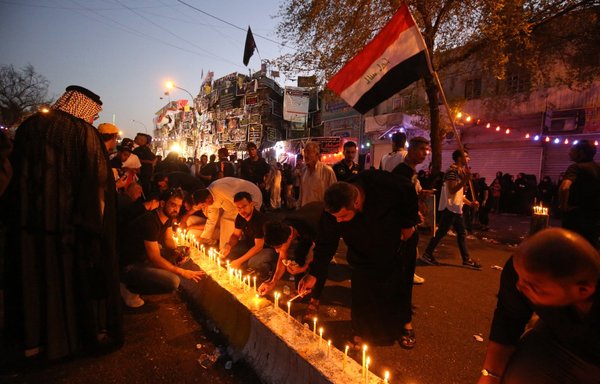 مردم عراق ۱۹ تیر ۱۳۹۵ در محل یک بمبگذاری انتحاری شمع روشن کردهاند؛ روز ۱۳ تیر همان سال، یک بمبگذاری انتحاری در حین خرید مردم برای تعطیلات عید فطر در محله الکراده بغداد رخ داده بود.