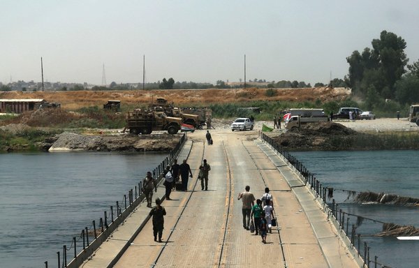 عراقيون يعبرون جسرا يربط بين غرب وشرق الموصل في 13 تموز/يوليو 2017، بعد أيام قليلة من إعلان الحكومة "تحرير" المدينة المحاصرة من داعش. [صافين حامد/وكالة الصحافة الفرنسية]