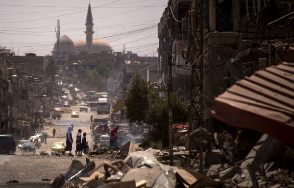 در روز ٢١ تیرماه ١٣٩٦ و چند روز پس از اعلام دولت مبنی بر «آزادسازی» موصل اشغال شده به دست داعش، عراقی‌ها در خیابانی آسیب دیده در غرب موصل قدم می‌زنند. [فاضل ثنا/خبرگزاری فرانسه]