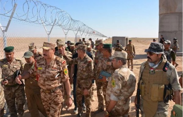 ضباط من حرس الحدود العراقية يتفقدون حاجزا من الأسلاك الشائكة يفصل بين الحدود العراقية والسورية في هذه الصورة التي التقطت في تموز/يوليو 2018.