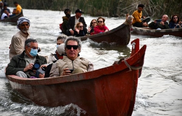 Spanish visitors of the Marshes of Jabayesh in southern Iraq ride boats as they tour the area, on February 25. [Asaad Niazi/AFP]