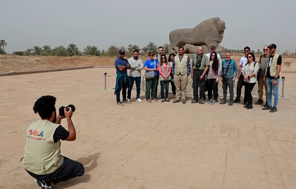 مرشد سياحي يلتقط صورة لسائحين أجانب يزورون مدينة بابل الأثرية في 7 آذار/مارس. [أحمد الرباعي/وكالة الصحافة الفرنسية]