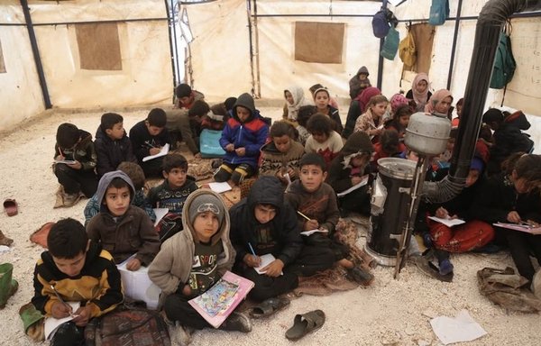 Syrian children sit on the ground as they attend class at al-Tah displacement camp. [Ali Haj Suleiman]