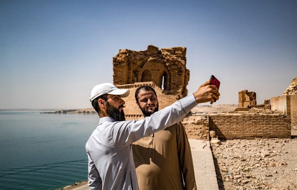 Men pose for a "selfie" photo at the ruins of Qalaat Jaabar in Syria's Lake Assad reservoir in al-Raqa province on June 3. [Delil Souleiman/AFP]